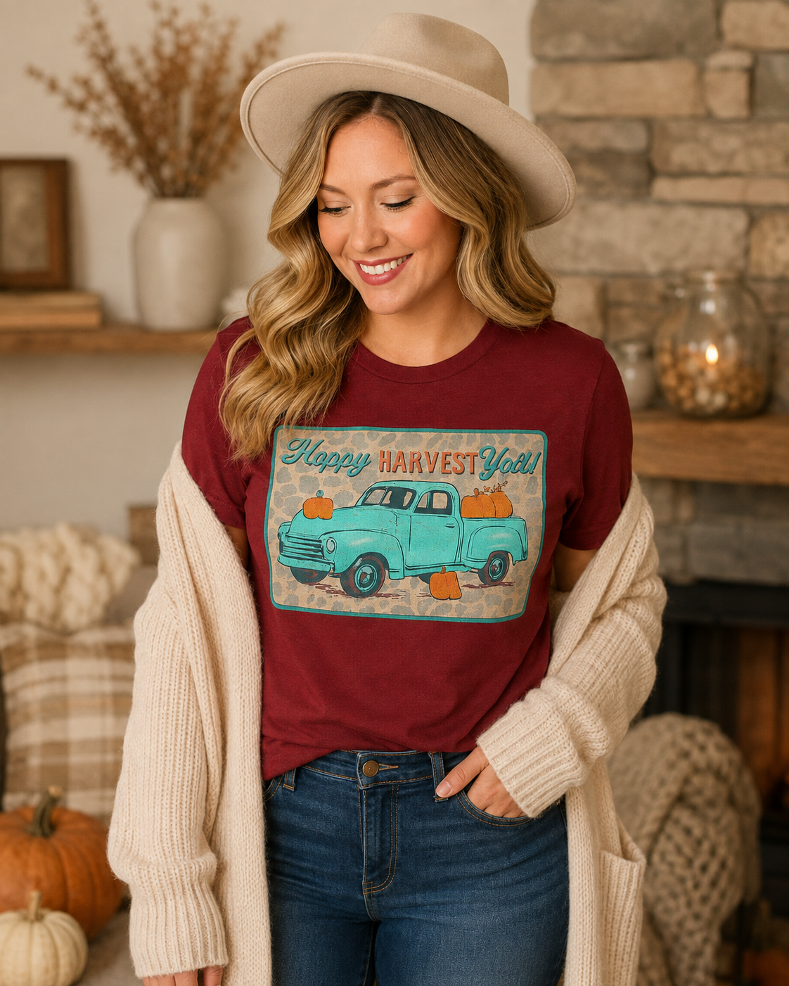 Woman wearing Harvest Roads burgundy graphic tee with a cream cardigan and neutral fall hat