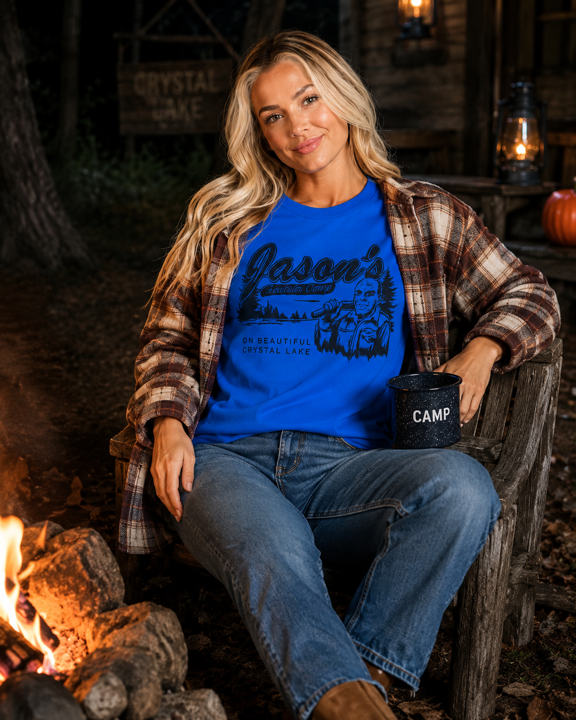 Emma wearing Crystal Lake Camp tee layered with a plaid overshirt beside a nighttime campfire