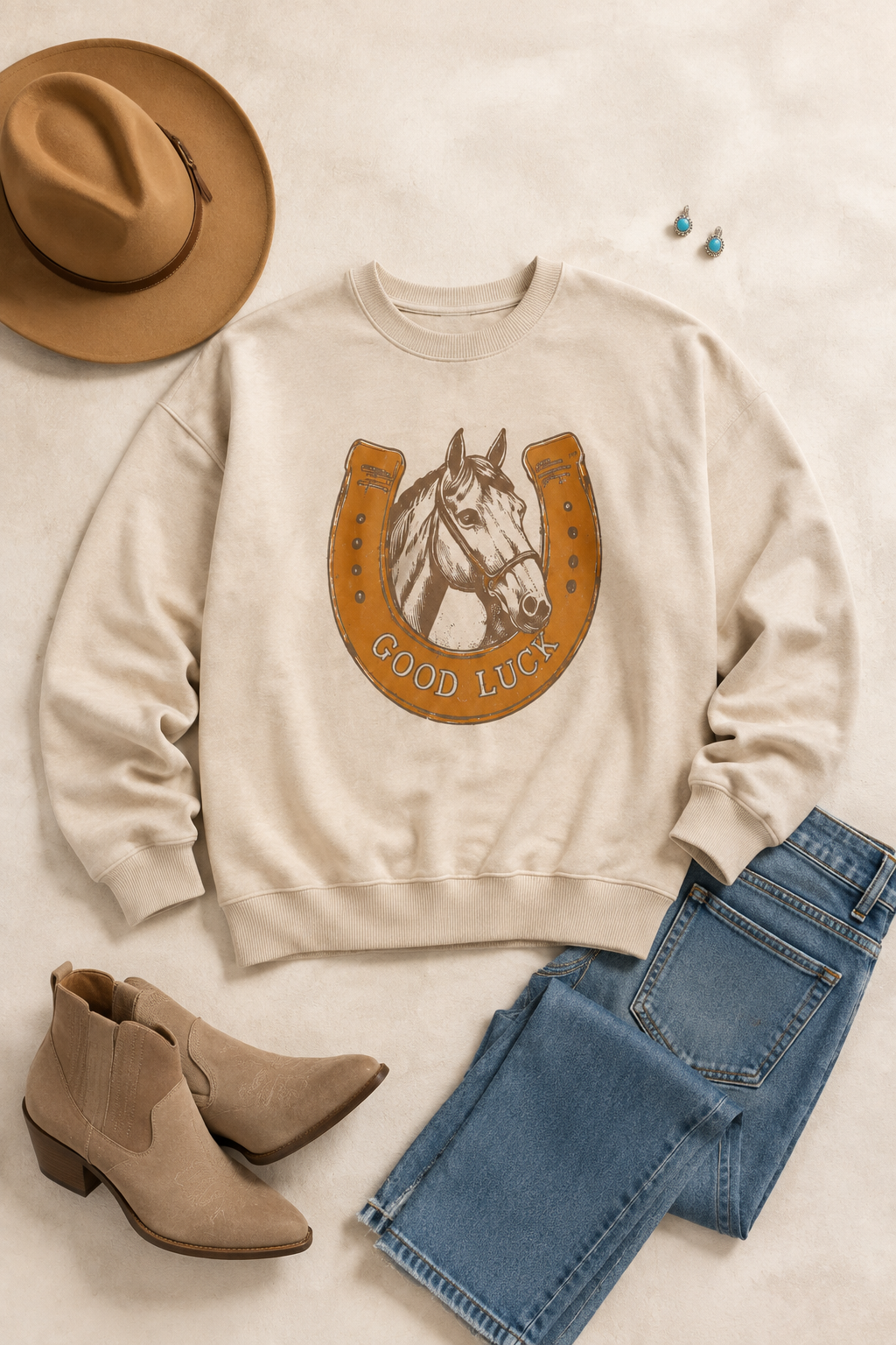 Beige GOOD LUCK horse graphic sweatshirt styled with jeans, taupe Western boots, cowboy hat and turquoise earrings.