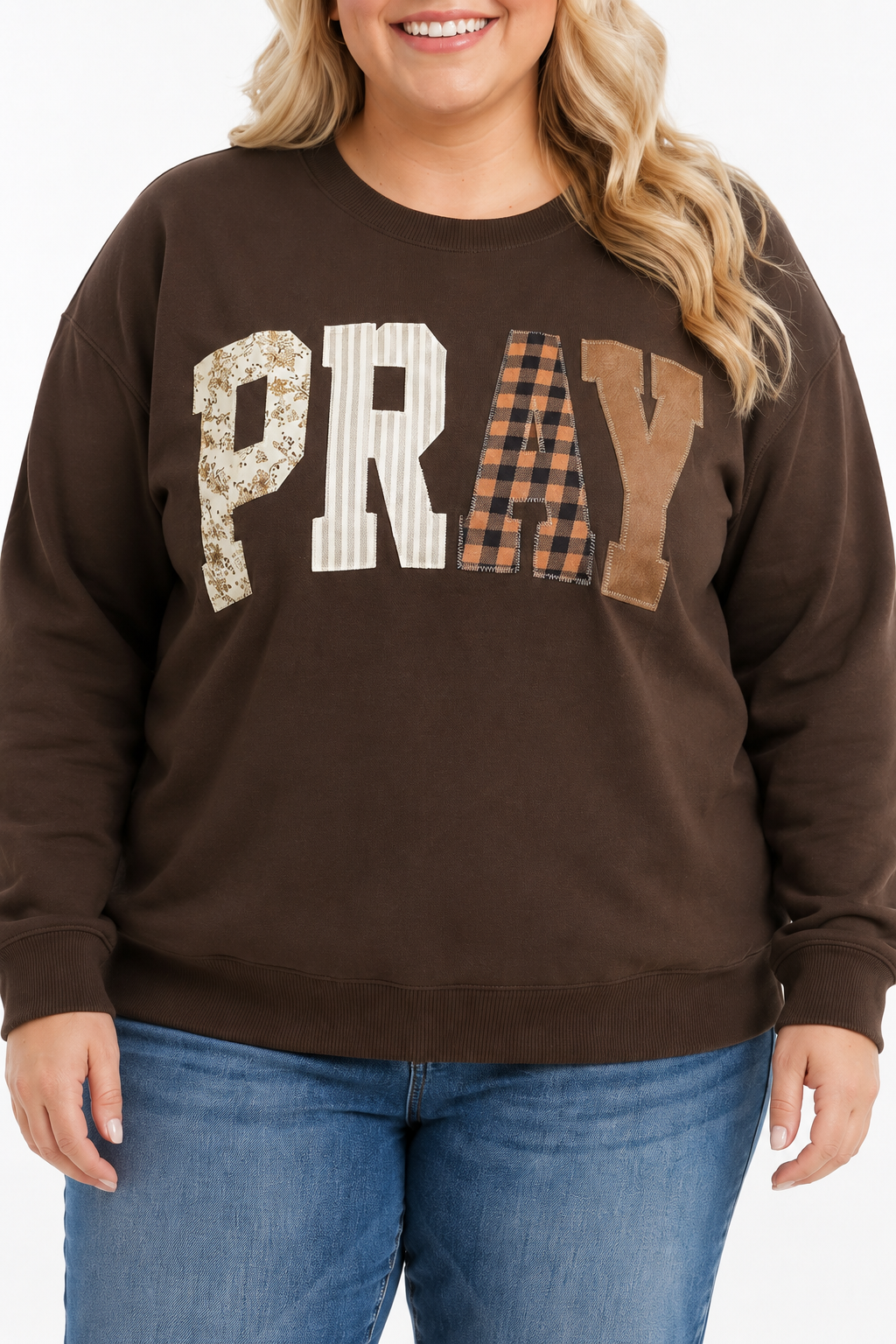 Close-up of coffee-brown plus-size sweatshirt featuring floral, striped, buffalo-plaid and camel PRAY fabric appliqué.
