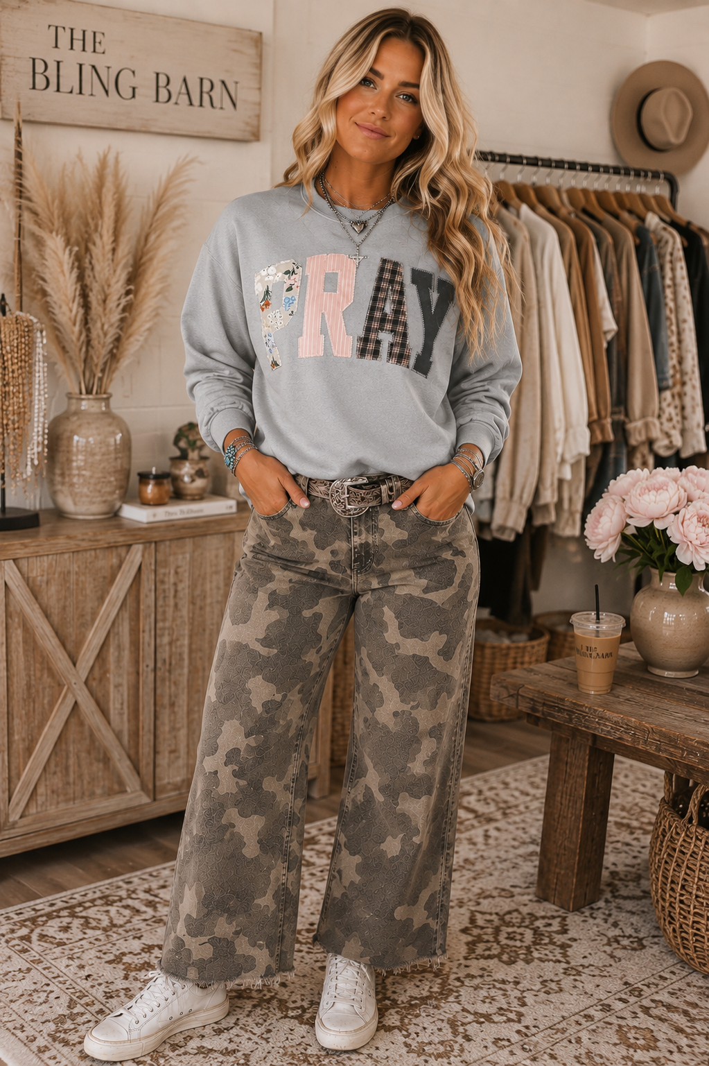 Emma wearing the gray Pray Through It patchwork sweatshirt with camo pants in The Bling Barn setting.
