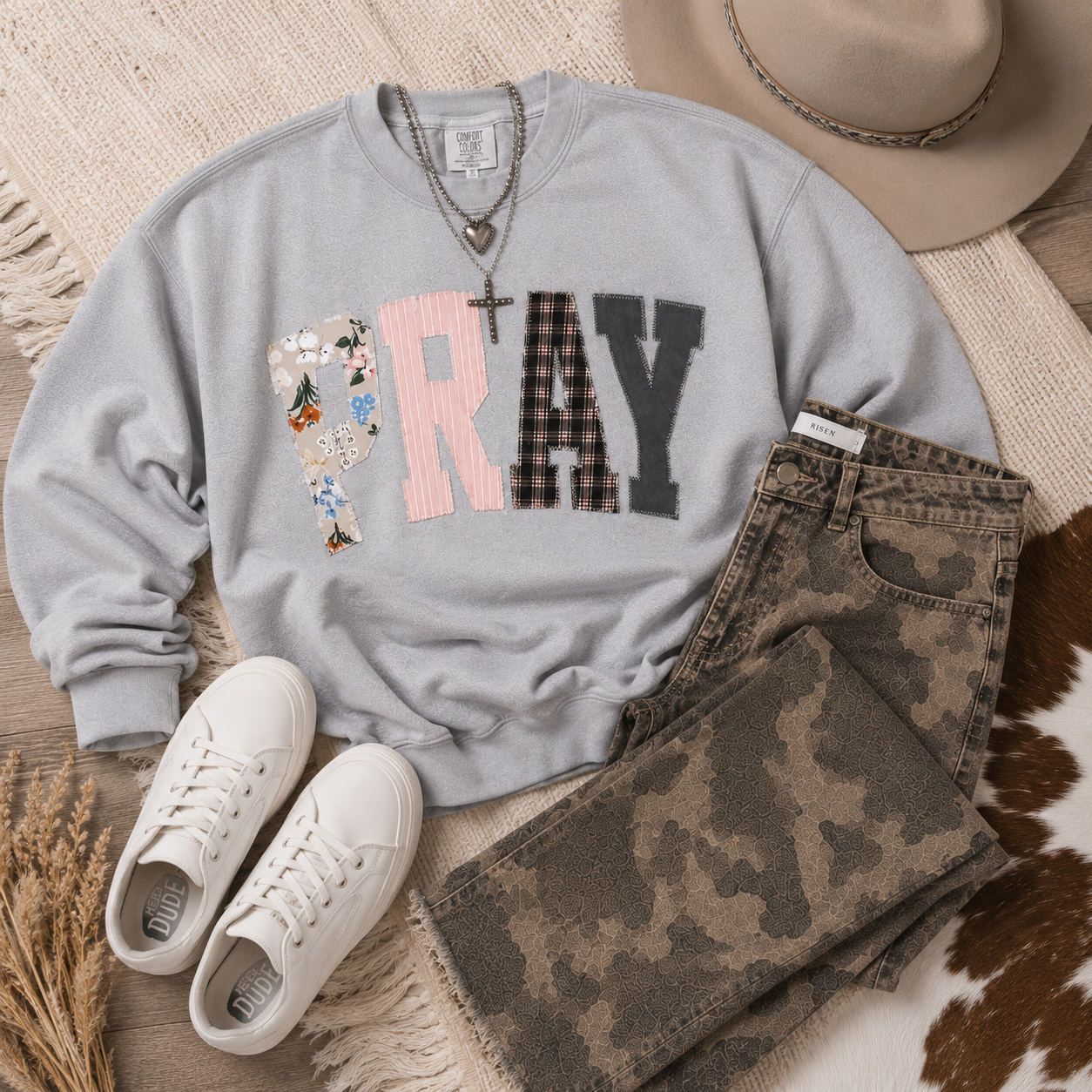 Gray Pray Through It patchwork sweatshirt styled in a Western-inspired flat lay with denim and neutral accessories.