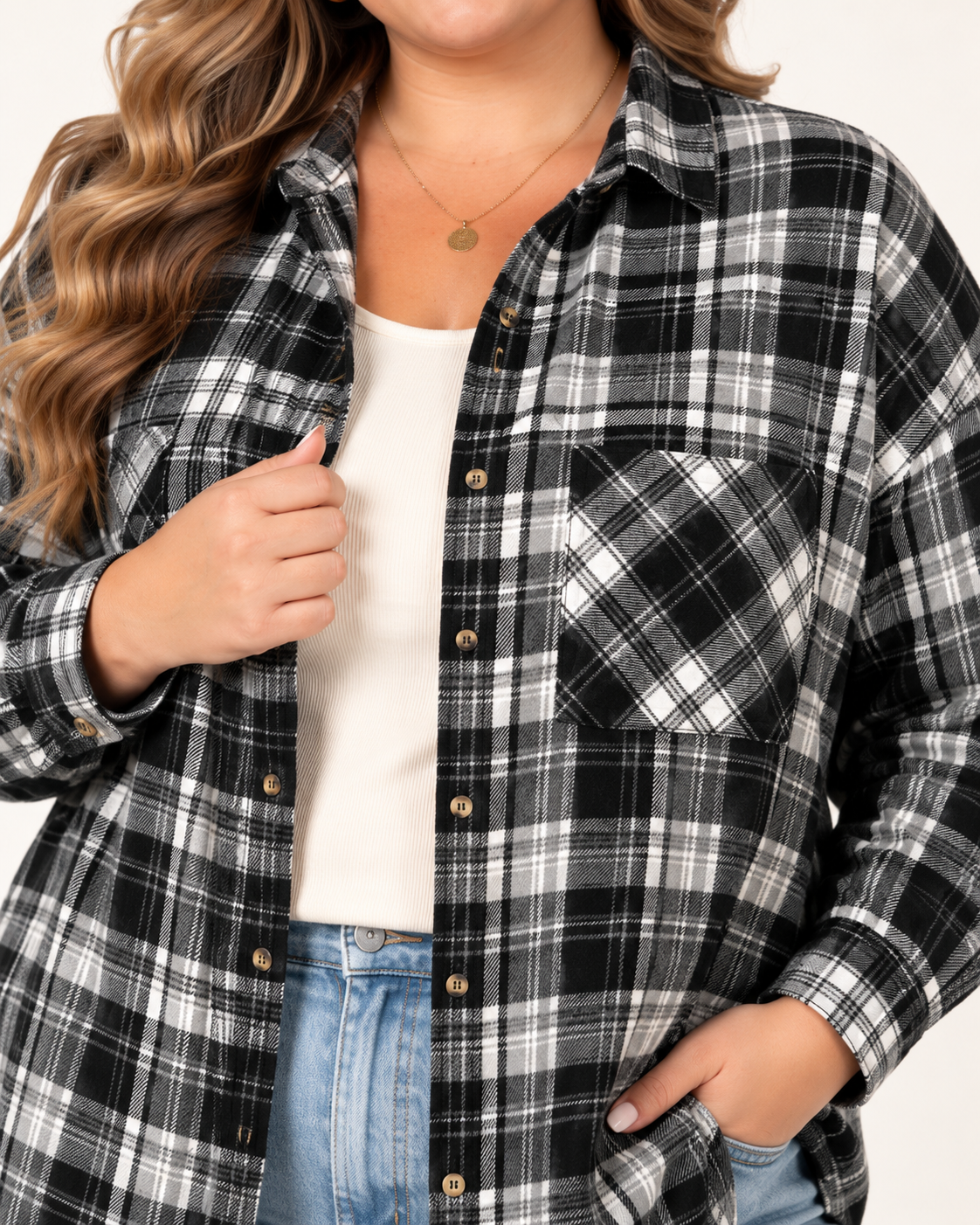 A woman wearing a black, white, and gray plaid button-up flannel shirt over a white tank top and blue jeans.