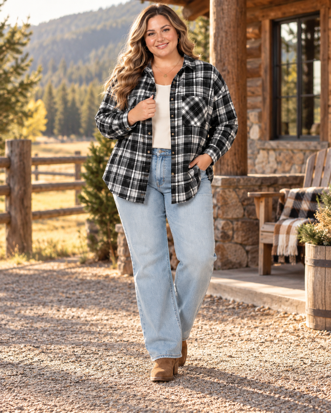 A woman stands outdoors in front of a rustic log cabin porch wearing a black-and-white plaid button-up flannel shirt over a white top, light blue jeans, and brown boots.
