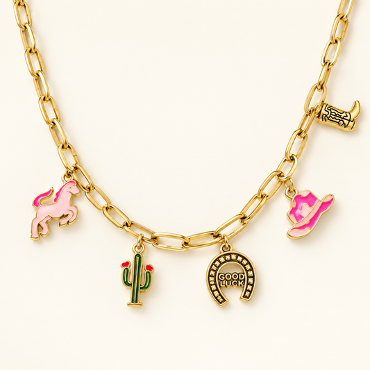 Golden rodeo western charm necklace with pink pony, cactus, cowboy hat, boot, and horseshoe charms on ivory background