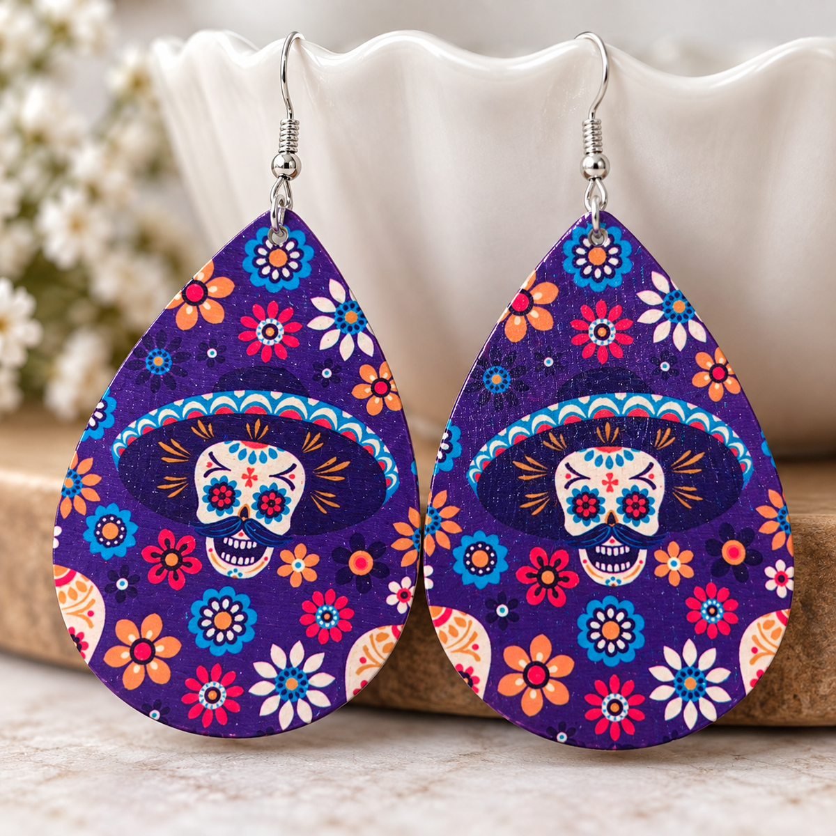 Midnight Fiesta wood earrings displayed on a neutral ceramic stand with bright floral accents