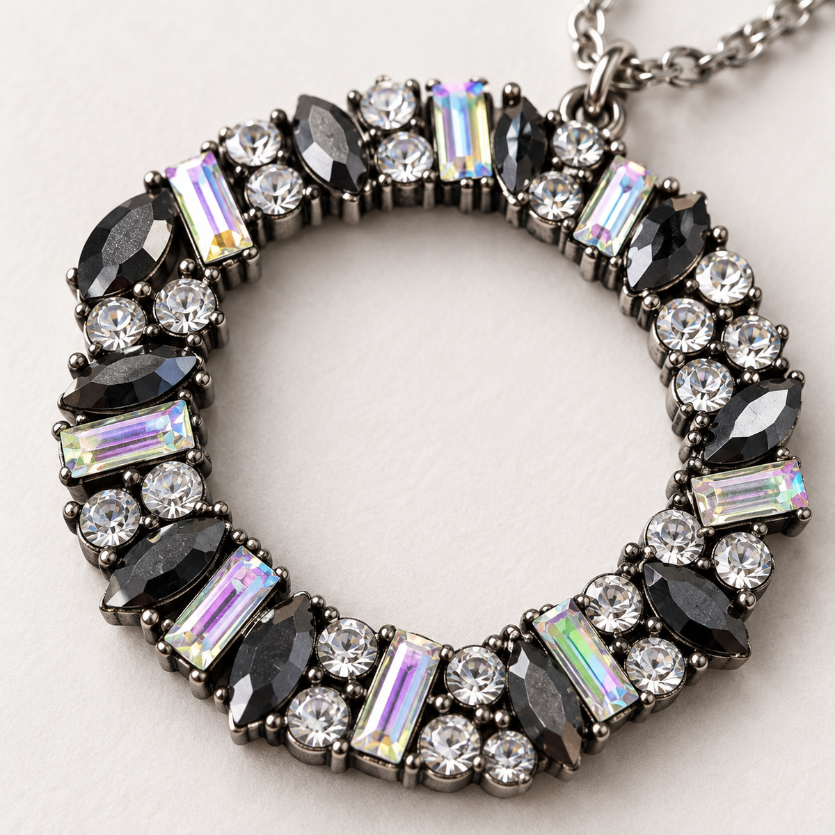 Close-up of circular pendant showing black marquise stones, clear rhinestones, and iridescent rectangular crystals