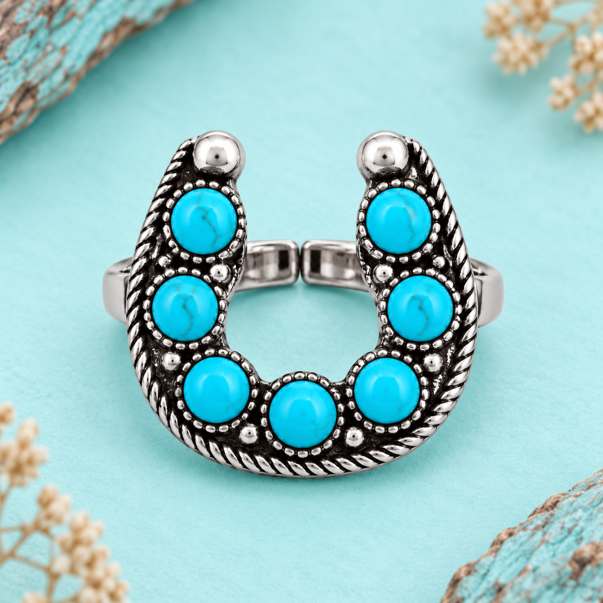 Western horseshoe ring with faux turquoise-colored stones styled on a turquoise background