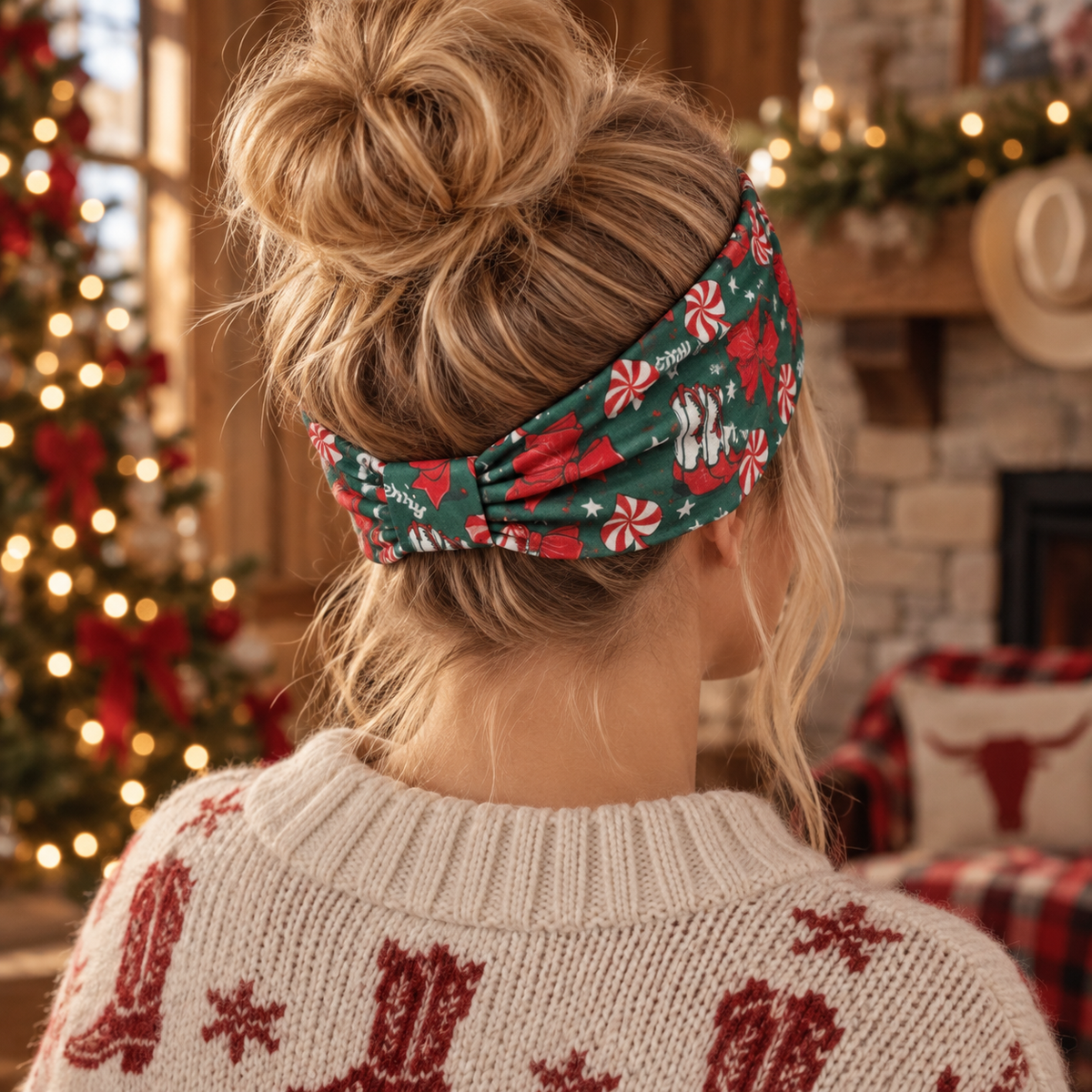A woman viewed from behind wearing a festive holiday headband with a red and green Christmas print, paired with a cream knit sweater in a cozy, warmly lit Christmas-themed room.