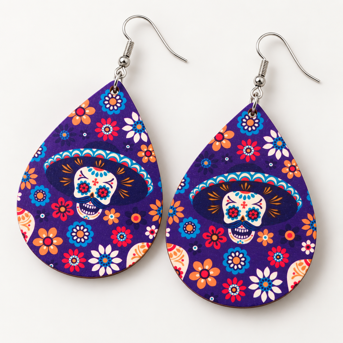 Close-up of purple wood teardrop earrings featuring colorful sugar skull artwork and silver-tone fish-hook wires