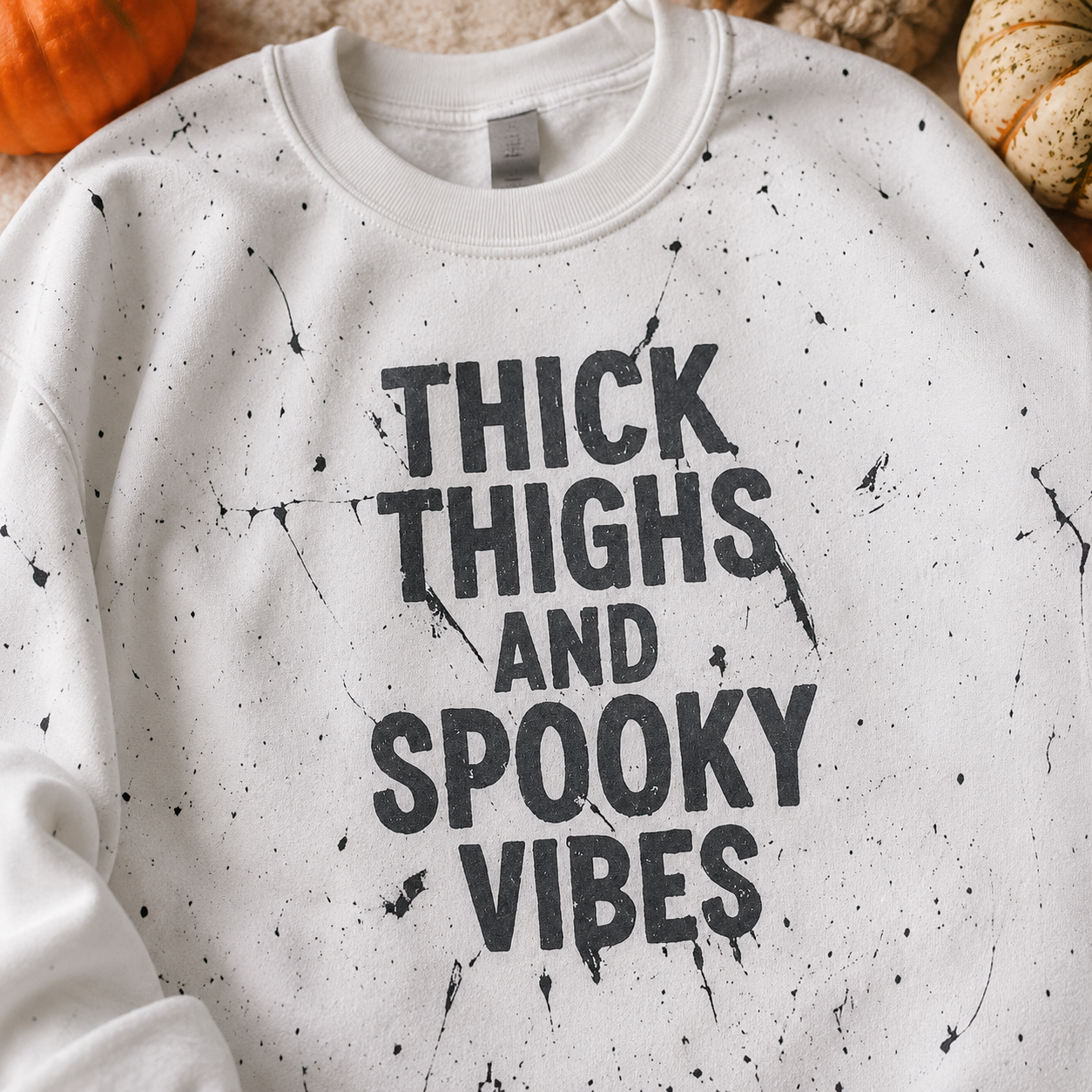 Close-up of Thick Thighs & Spooky Vibes sweatshirt showing distressed black lettering and paint-splatter details
