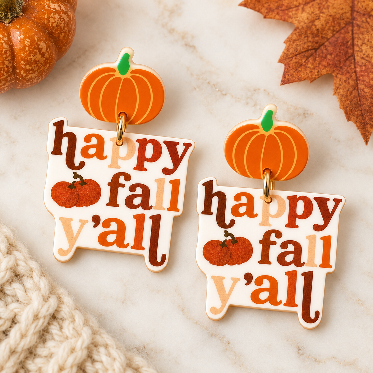 Happy Fall Y’all pumpkin acrylic earrings styled with autumn leaves and neutral fall decor