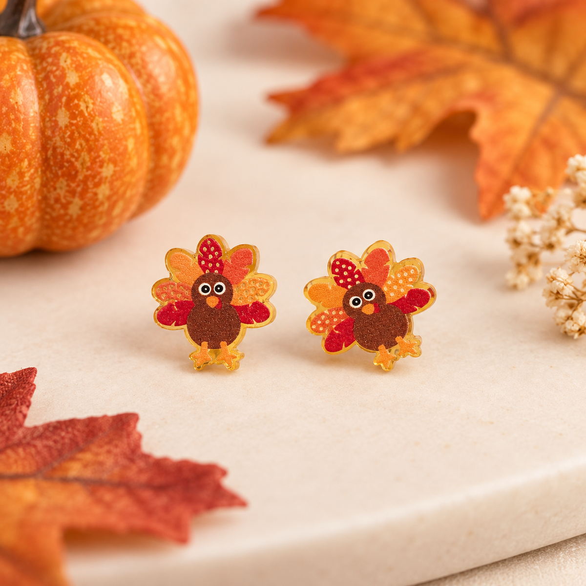 Little turkey acrylic stud earrings styled with pumpkins and autumn leaves