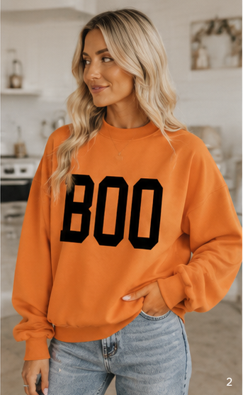 Emma wearing the reverse BOO side of the orange Halloween sweatshirt with relaxed denim styling.
