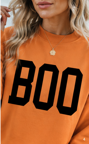 Close-up of the reverse BOO side showing the bold black lettering across the orange Halloween sweatshirt.