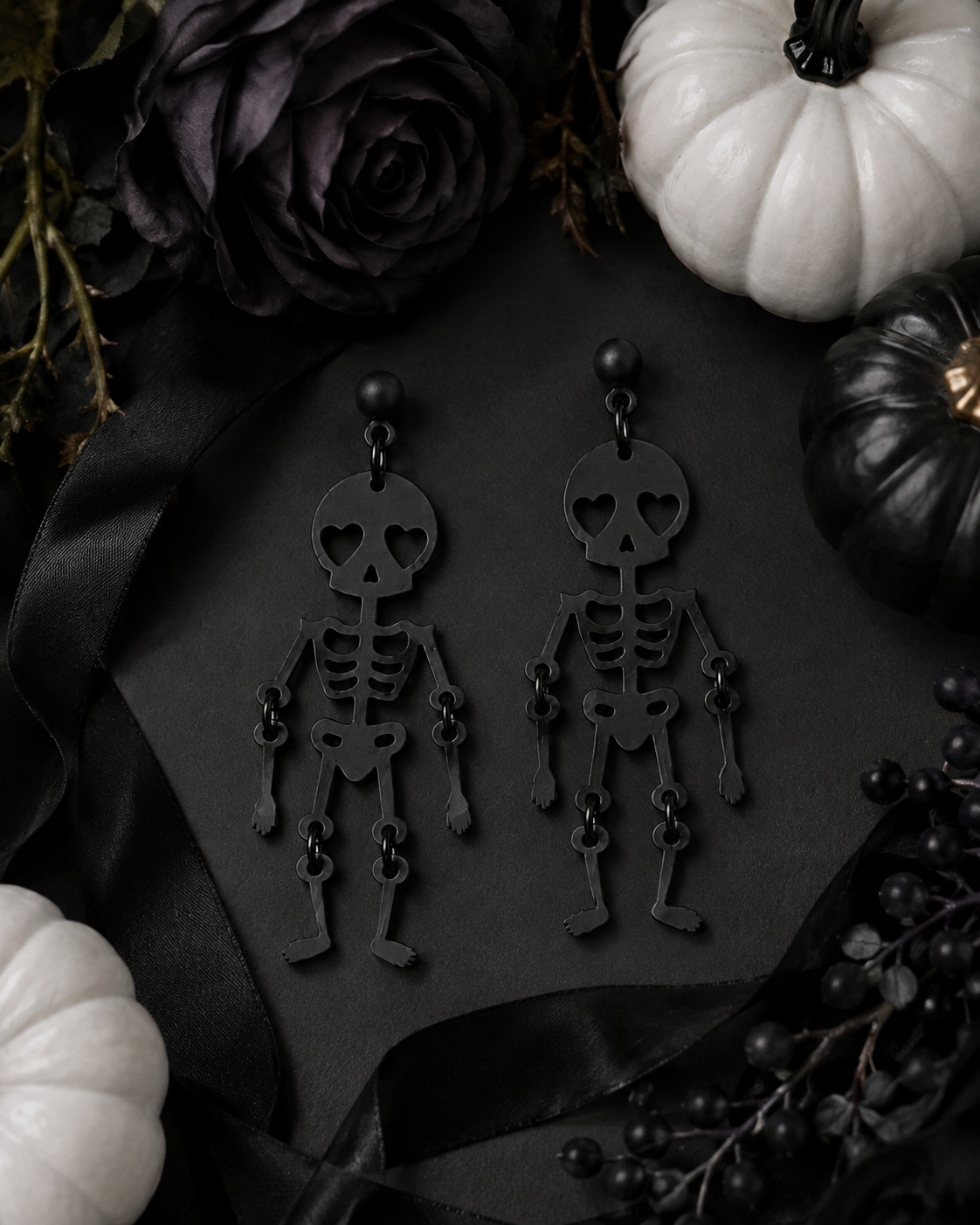Love You to Death skeleton earrings styled with black roses, ribbon and white and black pumpkins