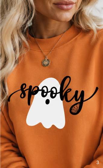 Close-up of the spooky ghost side showing the white ghost graphic, black spooky script, and pumpkin-orange sweatshirt fabric.