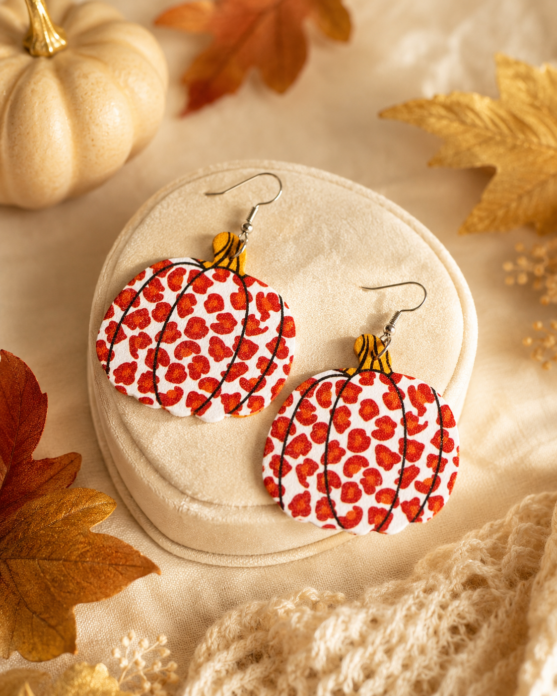 Wild Harvest Leopard Pumpkin Earrings displayed on a soft neutral jewelry stand with elegant autumn styling.