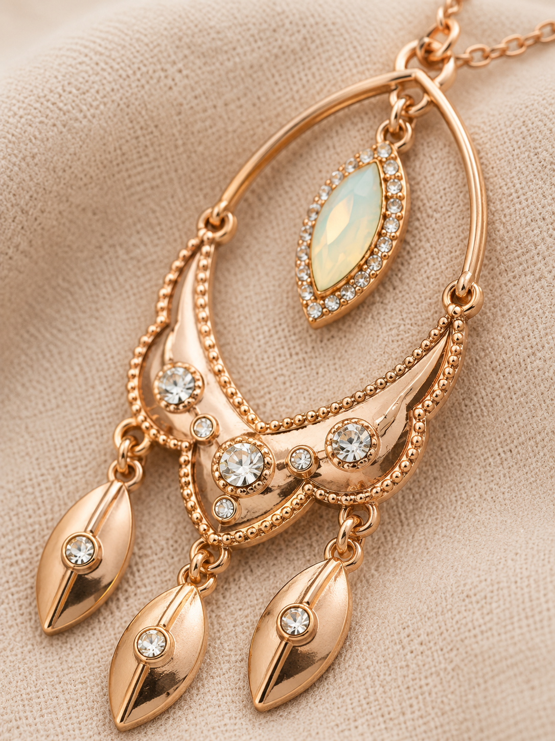 Close-up of Desert Glow pendant showing opalescent center stone, crystal detailing and three dangling rose-gold charms