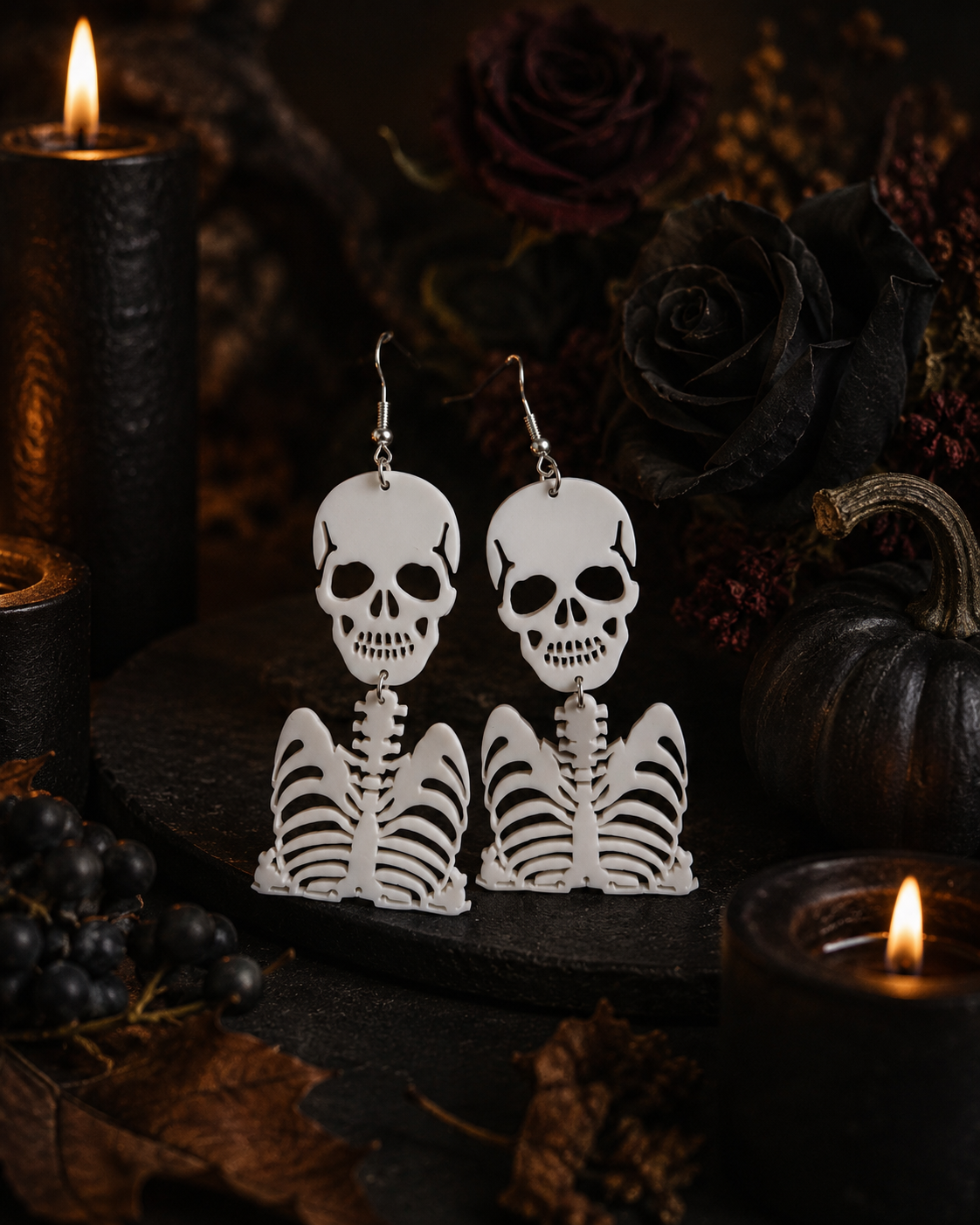 Ghostly Bones white skeleton earrings displayed in a moody candlelit Halloween setting with black roses
