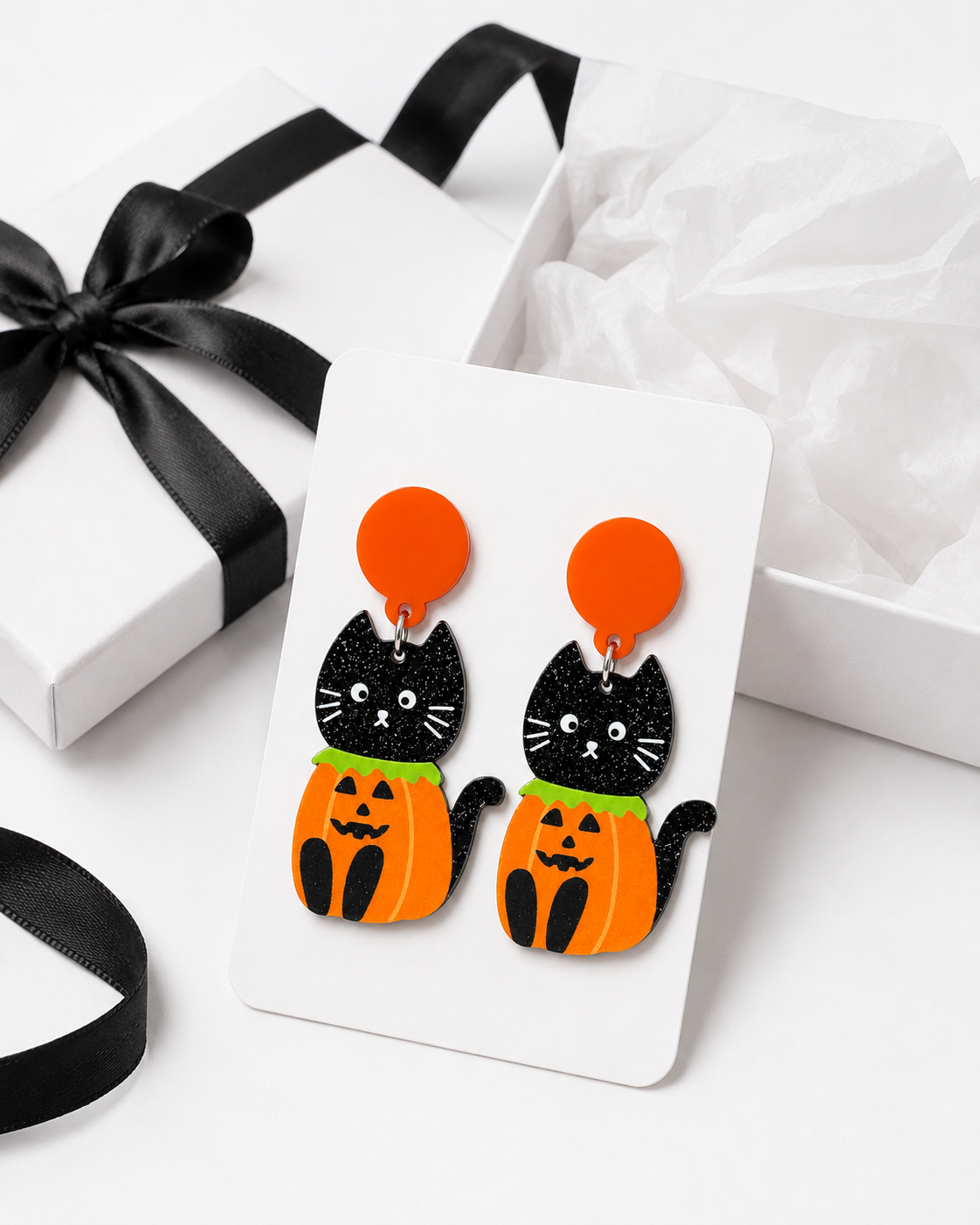Pumpkin Patch Kitty earrings displayed on a white jewelry card with gift box, tissue and black ribbon