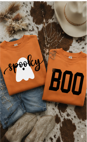 Flat lay of the orange reversible Halloween sweatshirt styled with denim, boots, gold jewelry, and subtle fall décor.