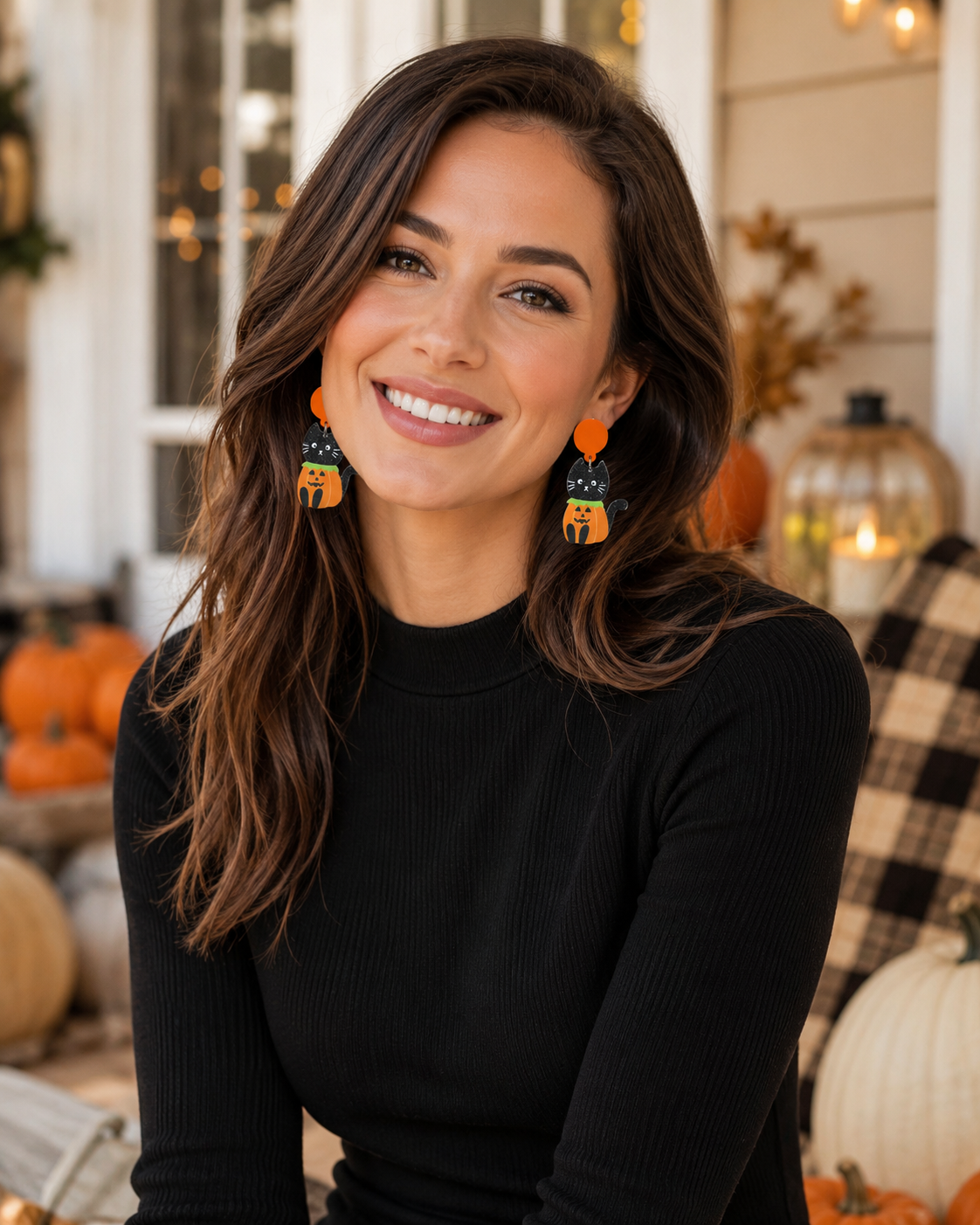 BlackWoman wearing Pumpkin Patch Kitty earrings with a black top in a cozy fall porch setting