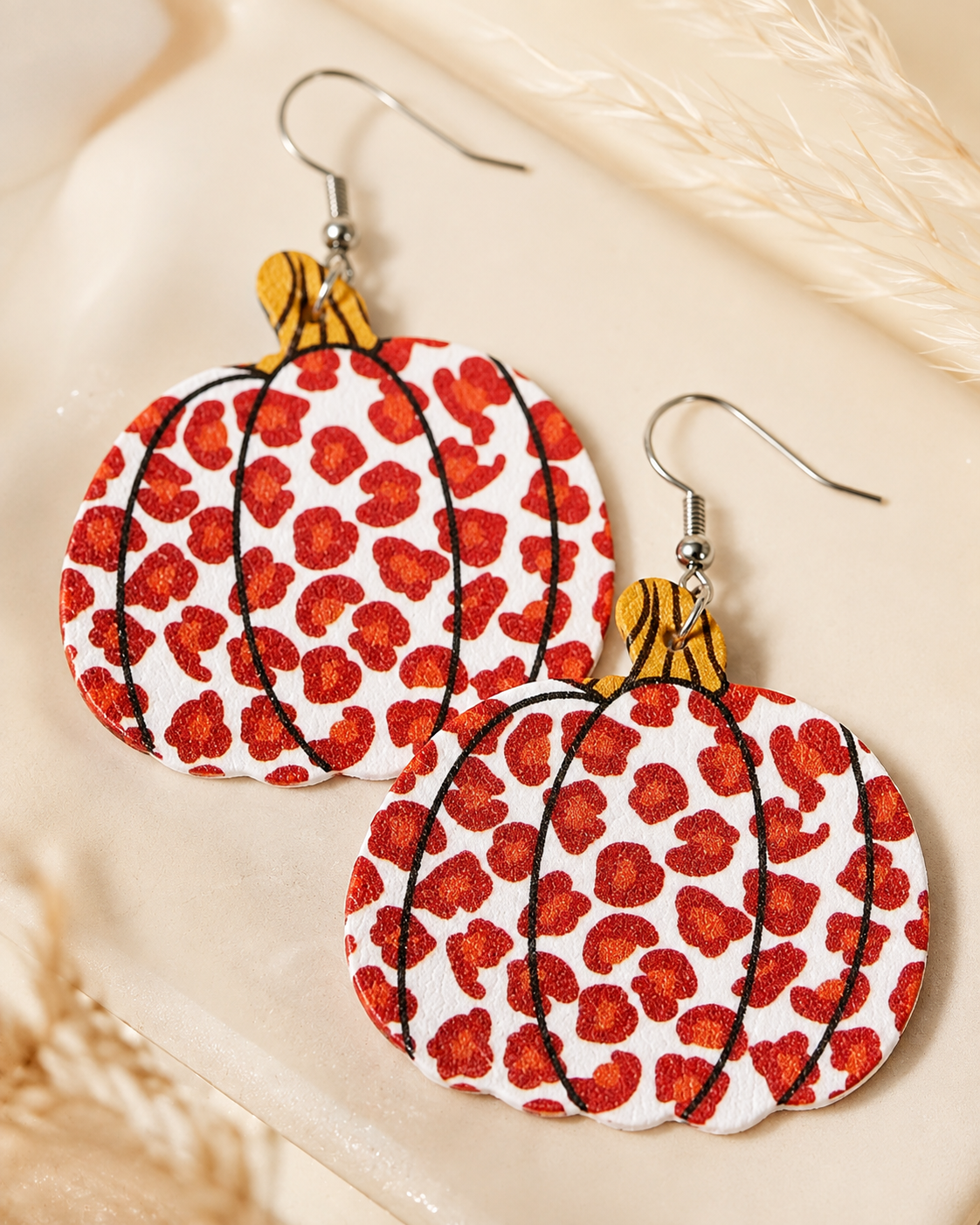 Close-up of Wild Harvest Leopard Pumpkin Earrings showing the rust leopard pattern, black pumpkin lines and golden-brown stems.