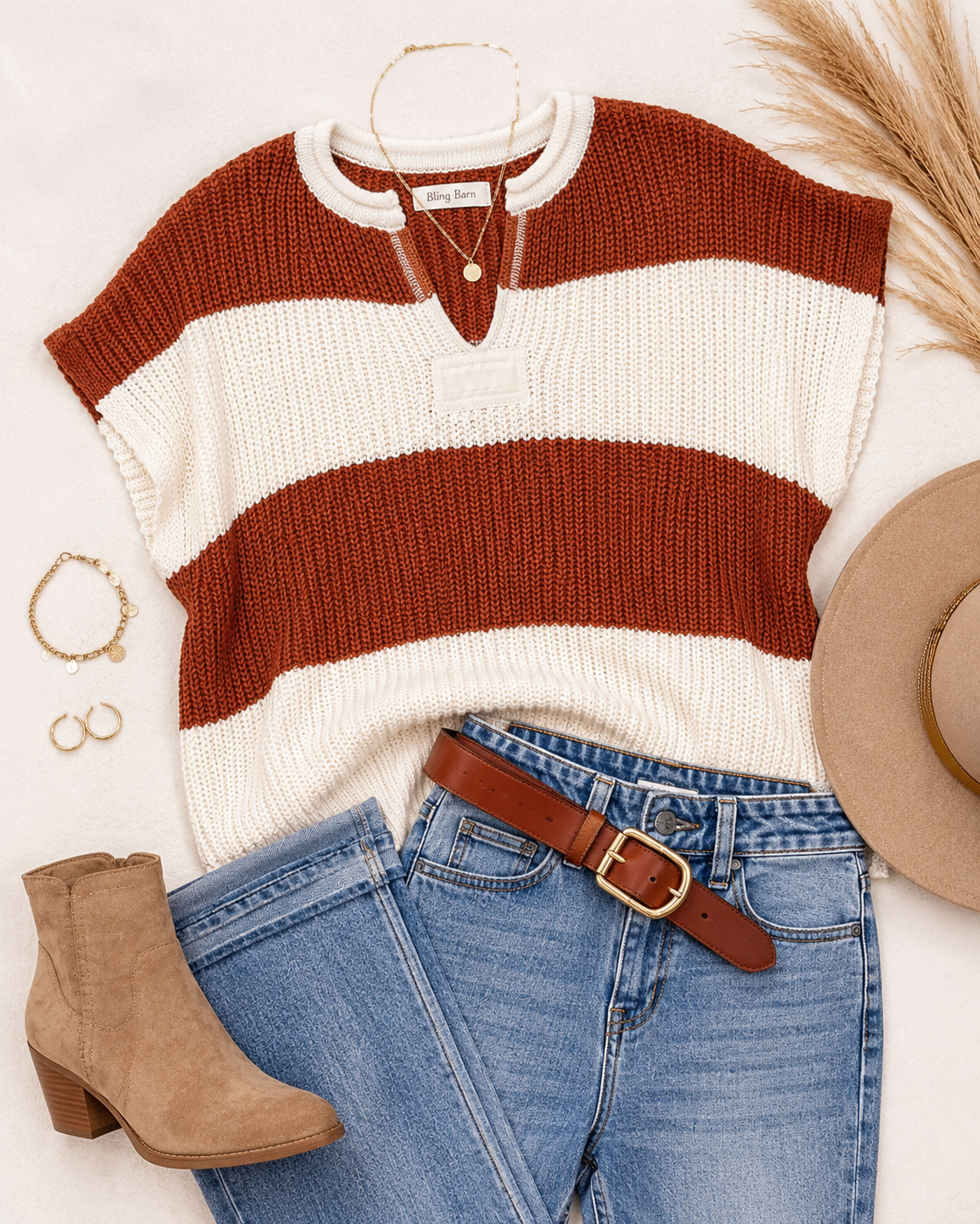Flat lay of the brown and ivory Saddle Stripe sweater with denim, leather belt, gold jewelry, hat, and ankle boots.