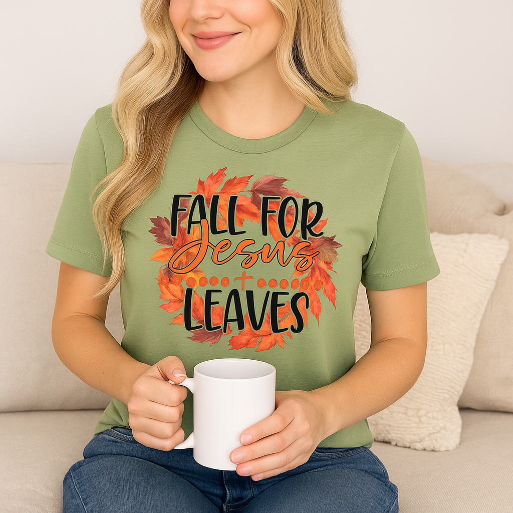 A woman wearing an olive green graphic t-shirt with a 'Fall for Jesus before the leaves' design, holding a white mug while sitting on a beige couch.