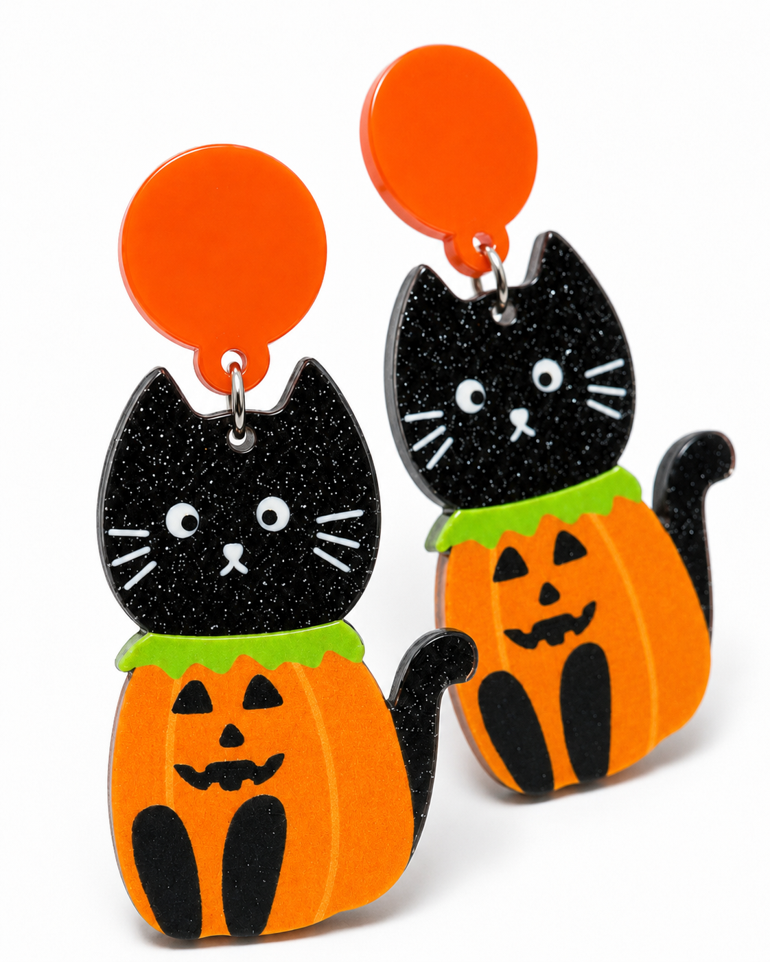 Close-up of black glitter cat and jack-o'-lantern earrings showing orange, green and white details