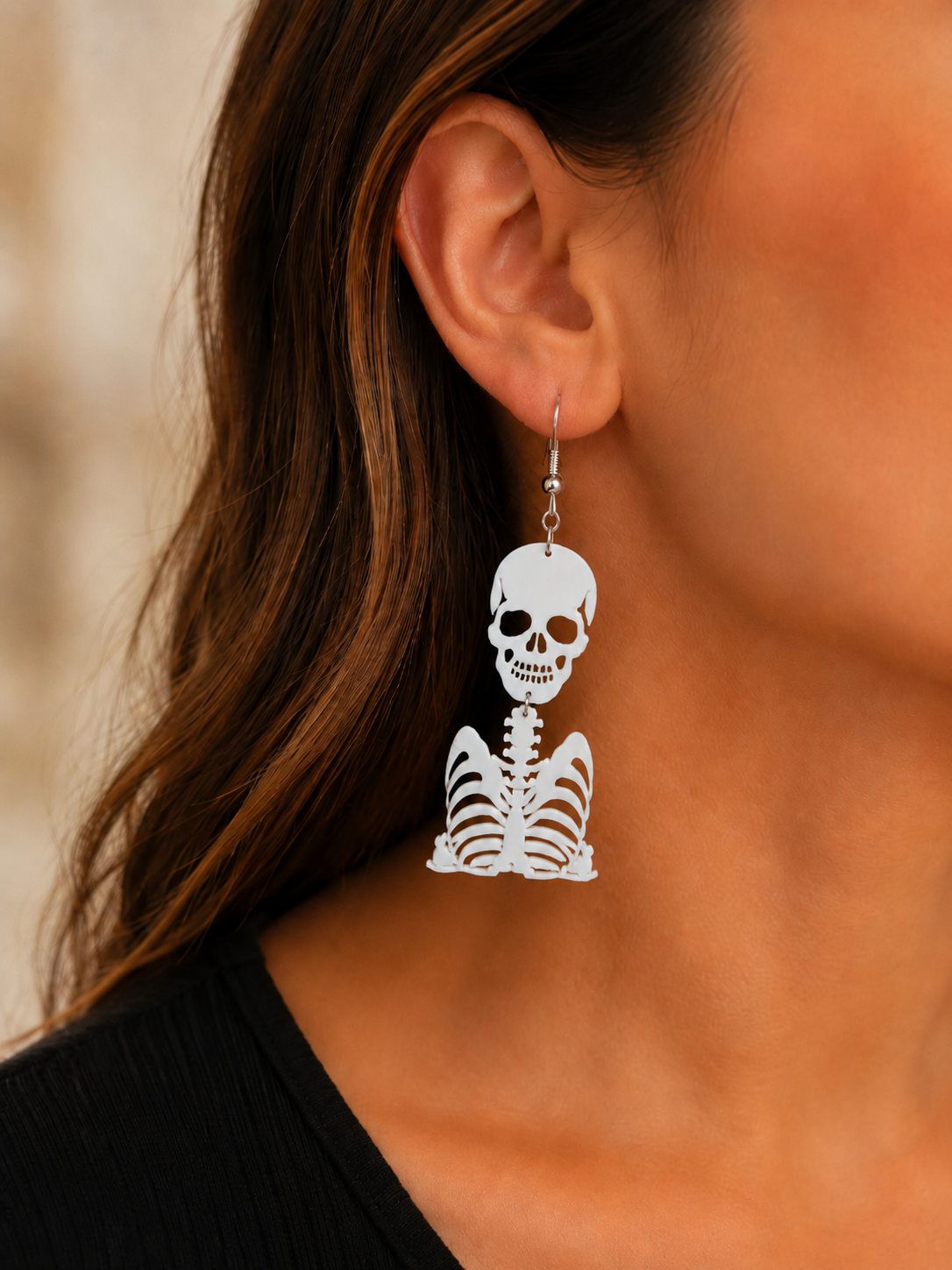 Close-up of woman wearing Ghostly Bones white skeleton statement earring with silver-tone hook