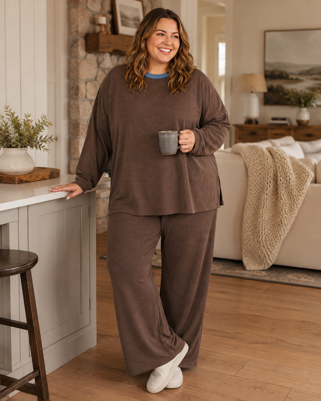 Curvy model wearing the Mesa Brown Relaxed Lounge Set while holding a coffee mug in a warm neutral home interior.