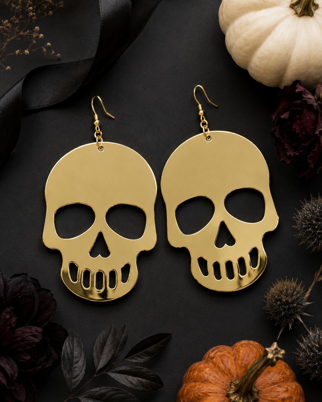 Gilded Afterlife gold skull earrings styled with pumpkins, black ribbon and dark florals for Halloween