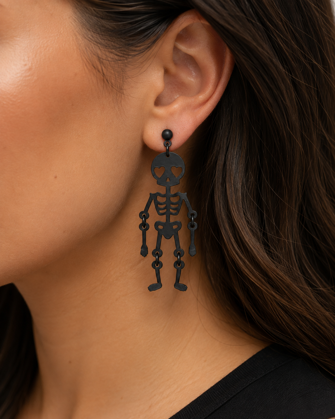 Close-up of woman wearing matte black heart-eye skeleton statement earrings