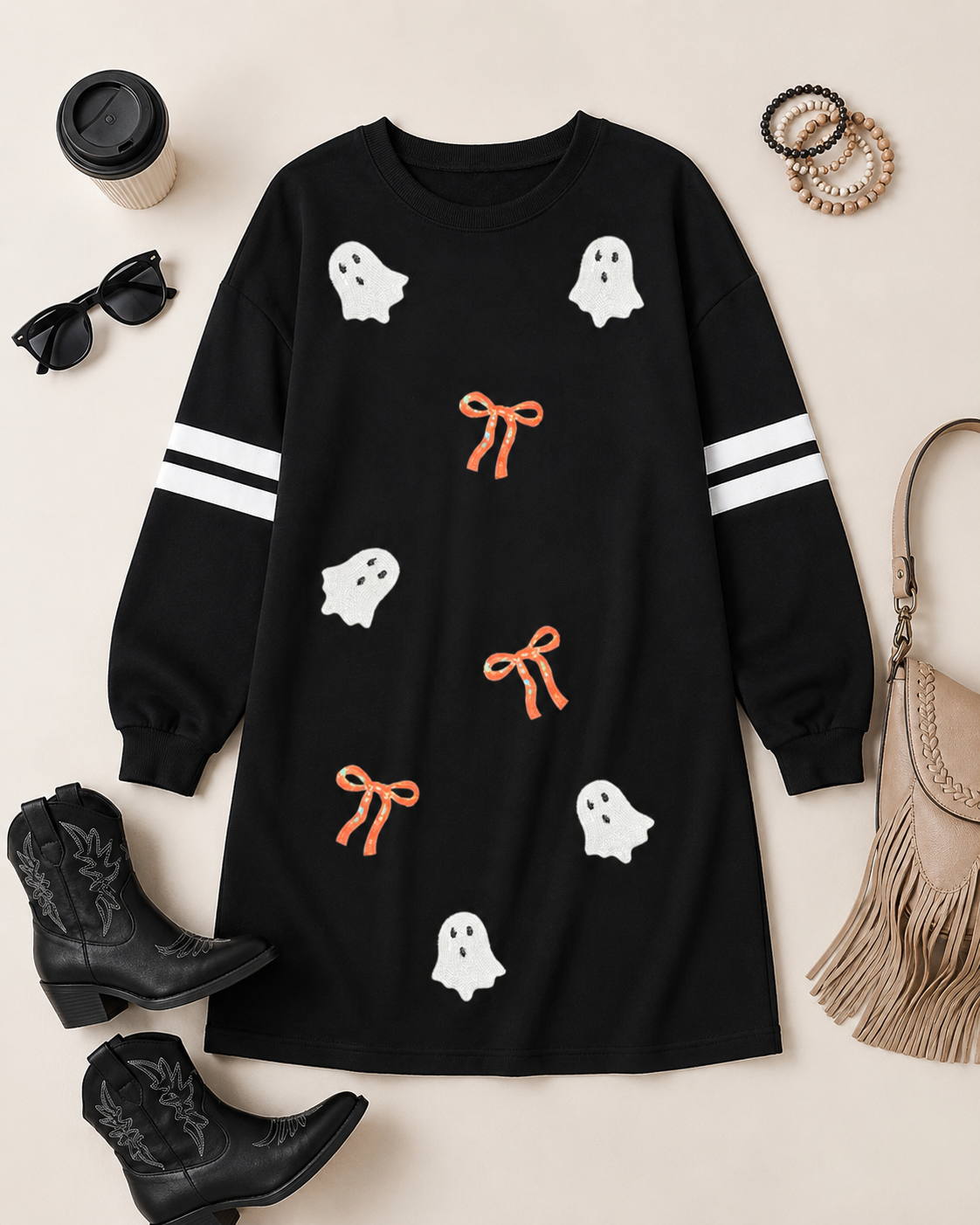 Flat lay of the black Ghost & Bow Varsity Sweatshirt Dress with black western boots, sunglasses, bracelets, coffee cup, and neutral fringe bag.